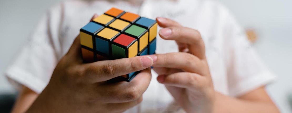Close-Up Photo of a Child Solving a Rubiks Cube